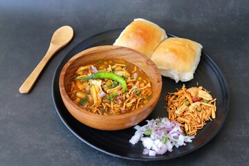 Spicy Misal Pav or usal Pav is a traditional snack or Chaat food from Maharashtra, India. Served with chopped onion, lemon wedges and farsan. Selective focus with copy space - obrazy, fototapety, plakaty
