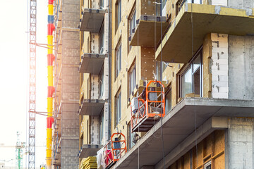 Suspended construction craddle near wall of hightower residentaial building with glass metal modern...