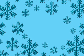 Fototapeta na wymiar Decorative snowflakes pattern in modern style with hard shadows, flat lay. Toy snowflakes on a blue background in the form of a seamless pattern. Irregular pattern, space for text.