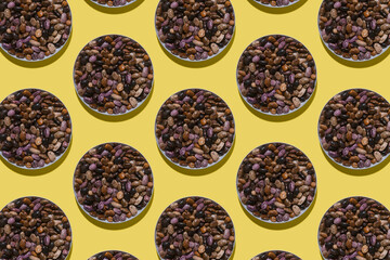 Colored beans pattern in modern style with hard shadows, flat lay. A plate with beans on a yellow background in the form of a seamless pattern. Regular pattern, top view.