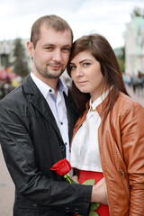 Portrait of a young couple with a red flower in their hands. - 435790476