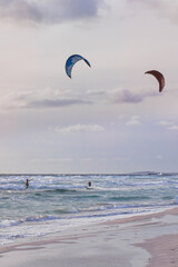 kitesurfers in the sky in the evening duck over the blue water of mediterranean sea