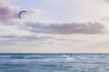 kitesurfers in the sky in the evening duck over the blue water of mediterranean sea