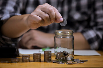Coins a men's hand  placed and sorted coins on a wooden board.