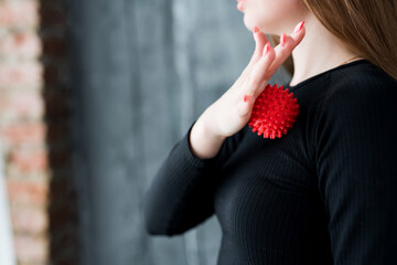 Close-up photo. A girl massages her pectoral muscles with her hand with a massage ball to relax the...