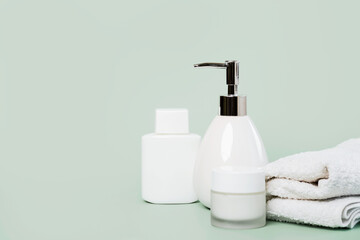 Fototapeta na wymiar Skincare products.Cream jar,lotion, liquid soap dispenser and towel with copy space