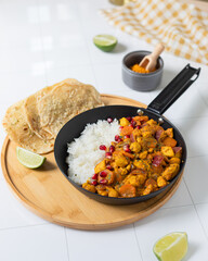 Chicken curry Indian cuisine dish with rice and naan bread in black pan on white background 