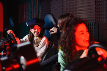 african american girl laughing near friends and car racing simulators