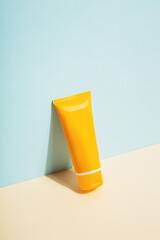 Orange tube of sunscreen on blue background. Sun Protection. Copy space