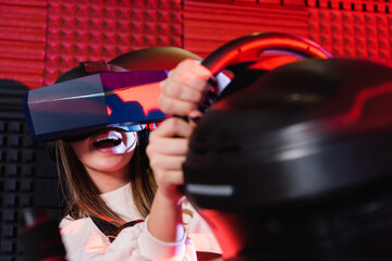 Fototapeta na wymiar amazed teenage girl racing in vr headset on car simulator, blurred foreground