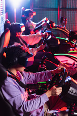 teenagers in vr headsets racing on car simulators on blurred background