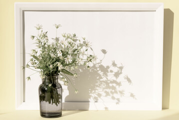 Creative composition made of bouquet of wild flowers in a gray glass vase on pastel background. Beautiful floral backdrop. Nature consept. Idea for seasonal cards and web design. Soft selective focus