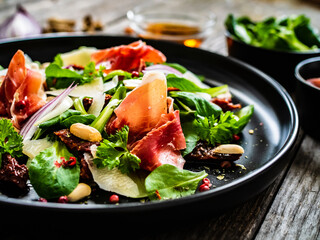 Tasty salad - ham, parmesan and fresh vegetables on wooden background
