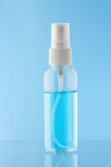 alcohol spray bottle isolated on a blue background, Translucent plastic spray bottle containing disinfectant alcohol.