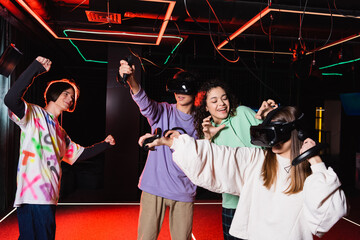 african american girl showing scaring gesture near friends in vr headsets