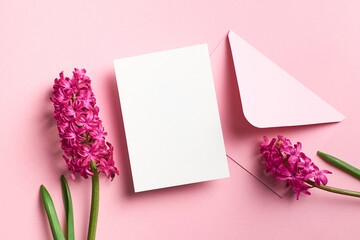 Invitation or greeting card mockup with envelope and spring hyacinth flowers on pink paper background