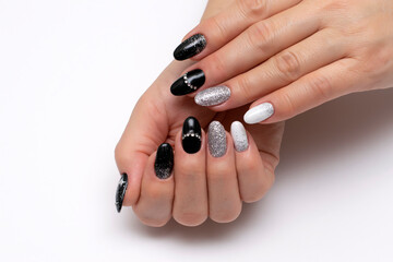 Black, white, silver manicure with crystals, painted stars and the moon on long oval nails close-up on a white background. Festive manicure.