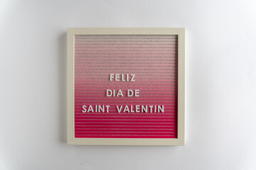Pink Board Words That Spell Feliz Dia De Saint Valentine (translation: Happy Valentine's Day), on a white background, horizontal