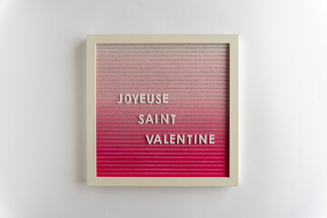 Pink Board Words That Spell Joyeuse Saint Valentin (translation: Happy Valentines), on a white background, horizontal