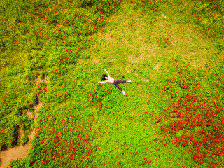 Aerial top view young caucasian woman lay in green field joyful spreaded hands. Well being and Feeling free and happy, self-loving optimistic nature shot.