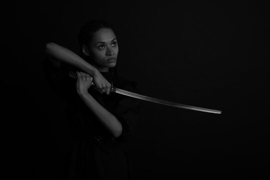 Beautiful woman with katana sword in darkness in black and white