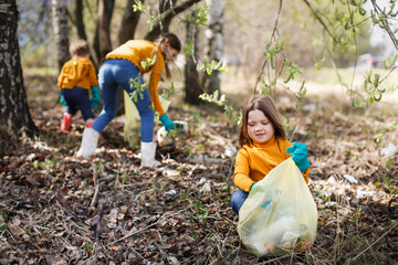 Young girl child with friends picking up trash in the park. Volunteer concept, Children picking up...