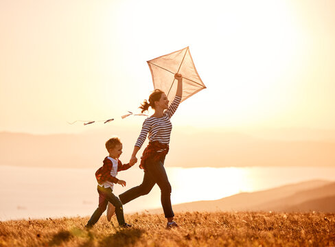 Happy family  mother and kid boy  launch  kite on nature at sunset