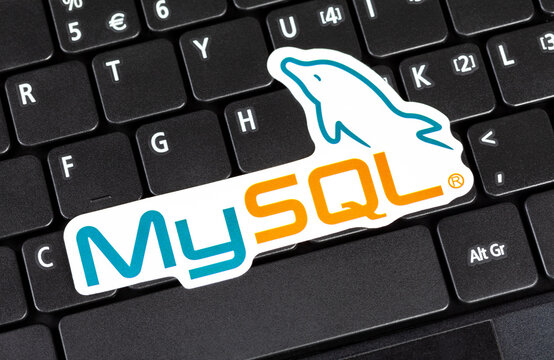 MySQL logo sticker laying on a laptop keyboard, object closeup, nobody. My SQL database technology symbol, website backend development, data management system