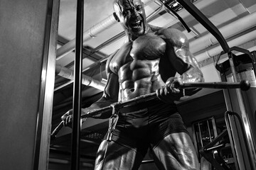 Fototapeta na wymiar Bodybuilder athlete trains in the gym. Sporty muscular guy with training apparatus. Sport and fitness motivation. Individual sports recreation with bodybuilding.