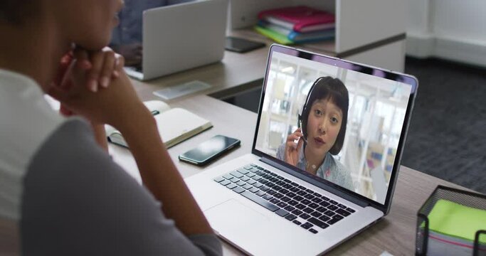 Mid section of african american woman having a video call on laptop with female colleague at office