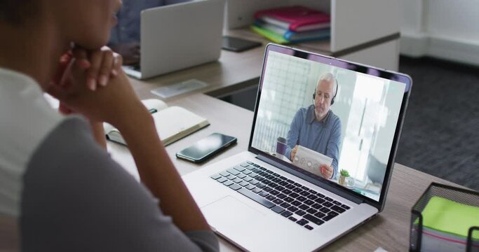 Mid section of african american woman having a video call on laptop with male colleague at office