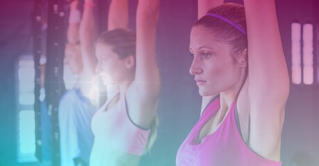 Strong women hanging from bar exercising in gym with pink tinted background