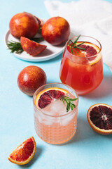 Blood orange cocktails with fresh fruits on blue table background. Summer cocktails, lemonade, refreshing drinks, low alcohol mocktail, party concept.