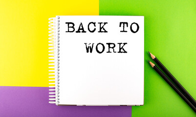 Minimal work space : sketchbook on the colorful background with BACK TO WORK text