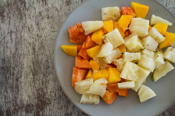 Gray plate on a rustic table containing cut fruits. Natural food. Tropical breakfast.
