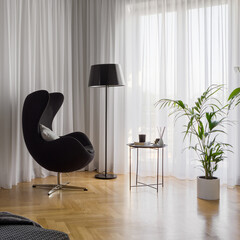 Black armchair in room with white curtains