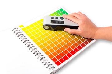 The hand is using a densitometer. A densitometer is an instrument used to measure the density of colors. It is commonly used in the printing industry and graphic design.