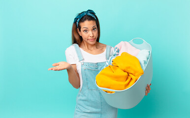 young hispanic woman feeling puzzled and confused and doubting and washing clothes