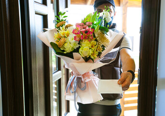 The delivery man delivers a bouquet of beautiful flowers to home