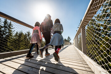 Family people walking wooden treetop bridge canopy walkway in winter.