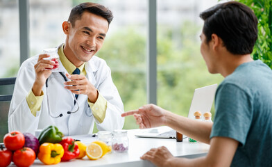 Happy Asian doctor showing vitamins to patient