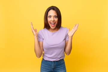young hispanic woman feeling happy and astonished at something unbelievable
