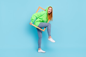 Photo of adorable funny young woman wear green sweatshirt walking photo frame looking empty space isolated blue color background