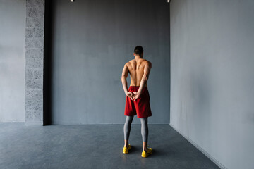 Fototapeta na wymiar Young shirtless sportsman doing exercise while working out indoors