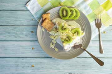 Homemade cheesecake with kiwi in a gray plate on a blue wood background top view
