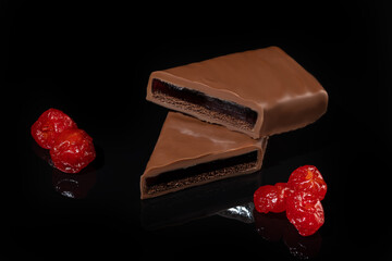 Chocolate candies on a dark background with reflection. Piece by piece and as a whole. Filling of nuts and fruits.