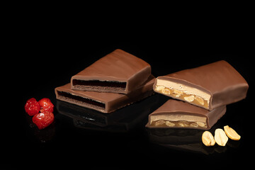 Chocolate candies on a dark background with reflection. Piece by piece and as a whole. Filling of nuts and fruits.