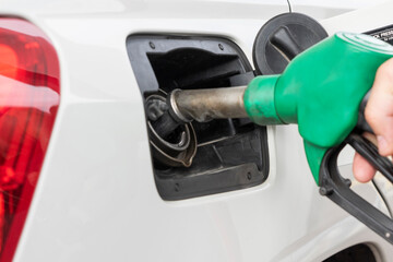 Close up image of green handle of gas pump in car's tank during process of refueling car.
