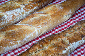 Fresh and crispy baguette on a red gingham napkin
