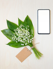 bouquet of lilies of the valley and smartphone. online flower shopping and delivery concept
